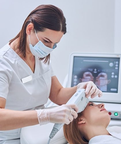 Close up side view portrait of elegant brunette cosmetologist in medicine mask with hydra vacuum cleaner taking facial peeling for beautiful lady in beauty center